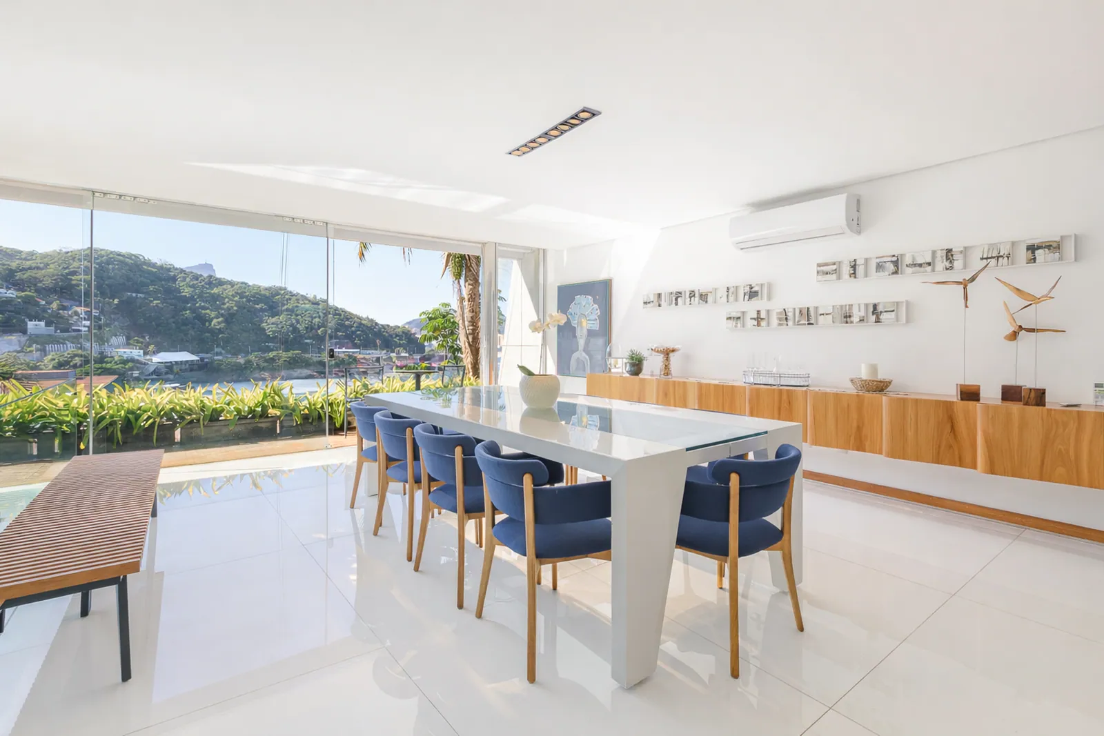 La mesa de comedor junto al cristal, jardín y piscina al fondo