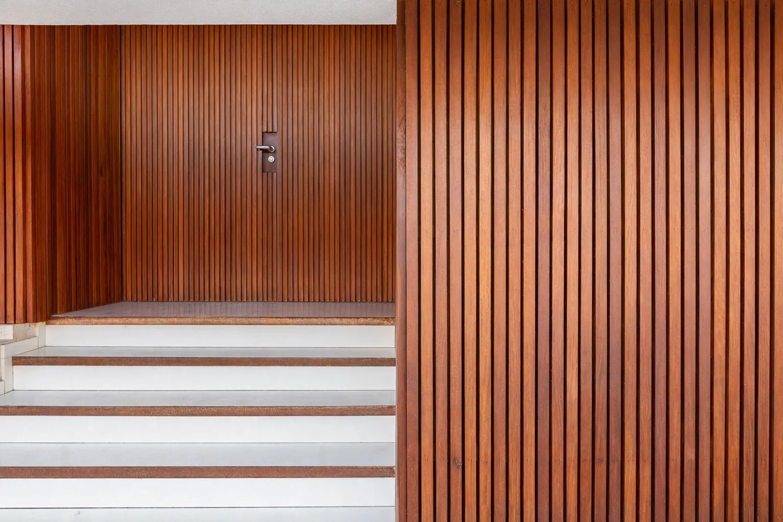 La entrada: un muro de listones de madera y un tramo de escalones