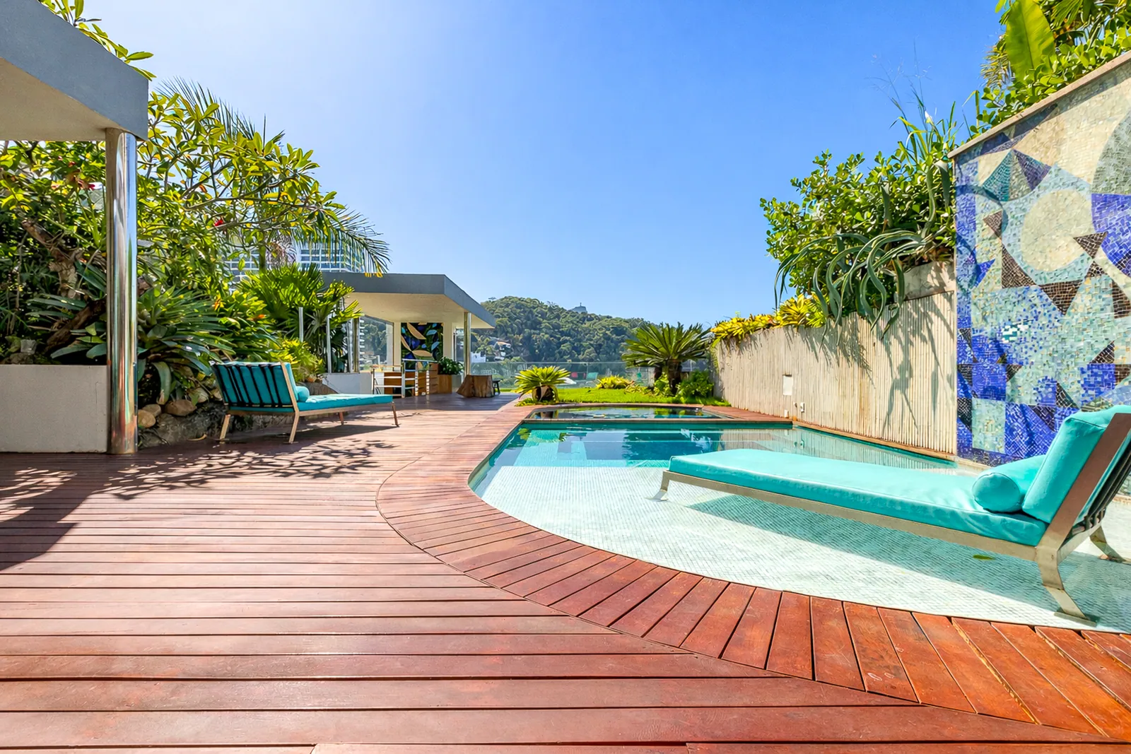 La piscina sobre la cubierta de madera, con un panel de mosaico al lado