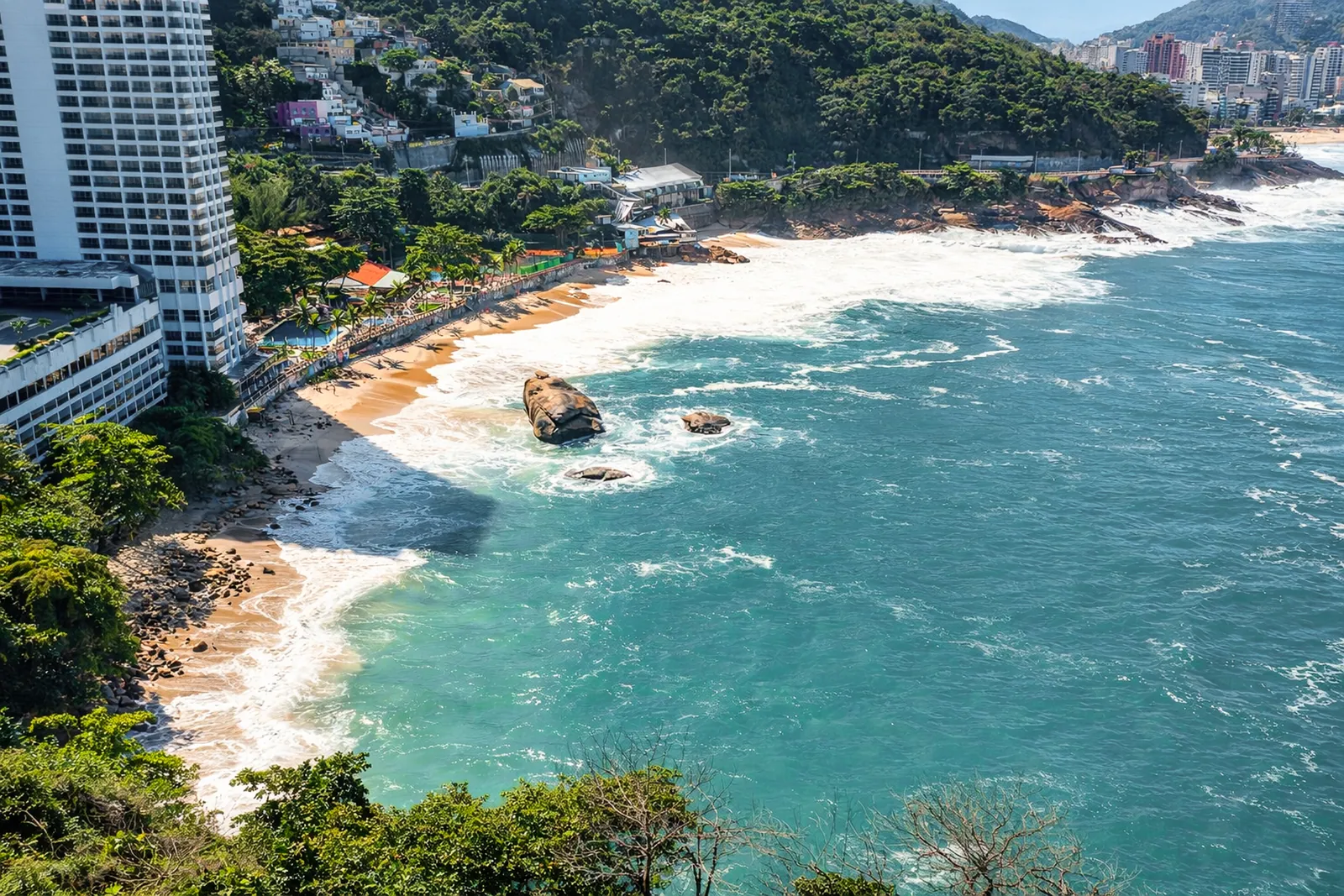 La cala y su playa desde el aire, rocas junto al agua