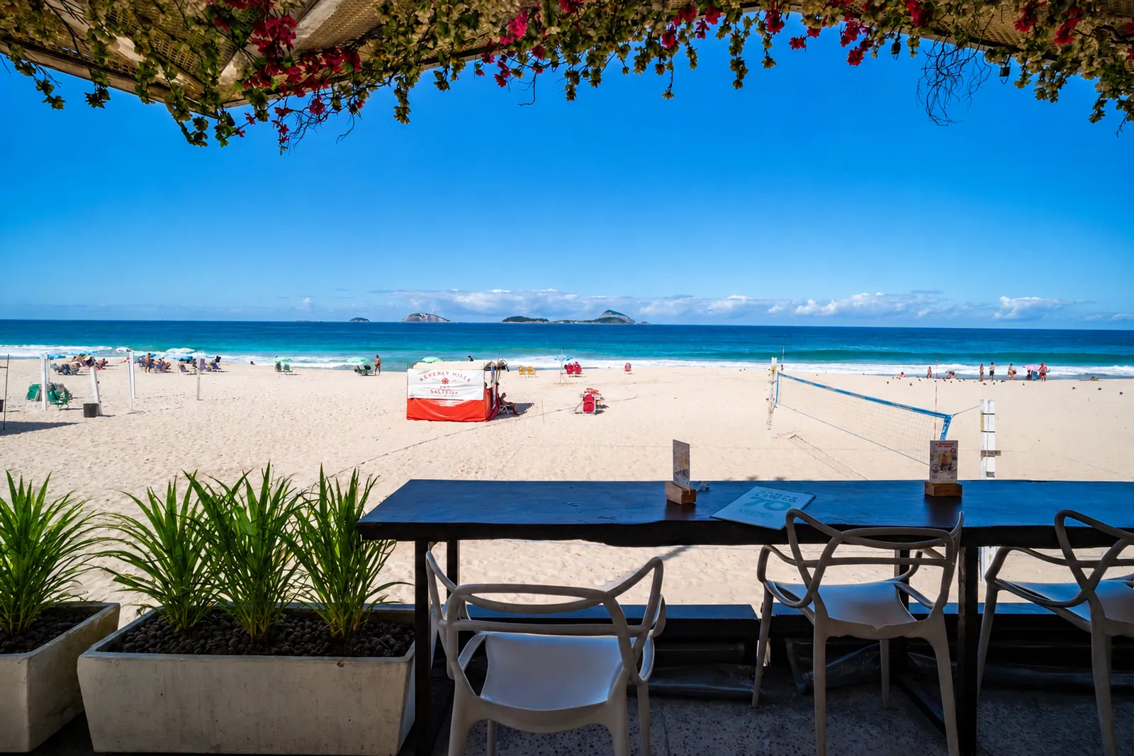 La playa vista desde la terraza de un restaurante, buganvillas arriba