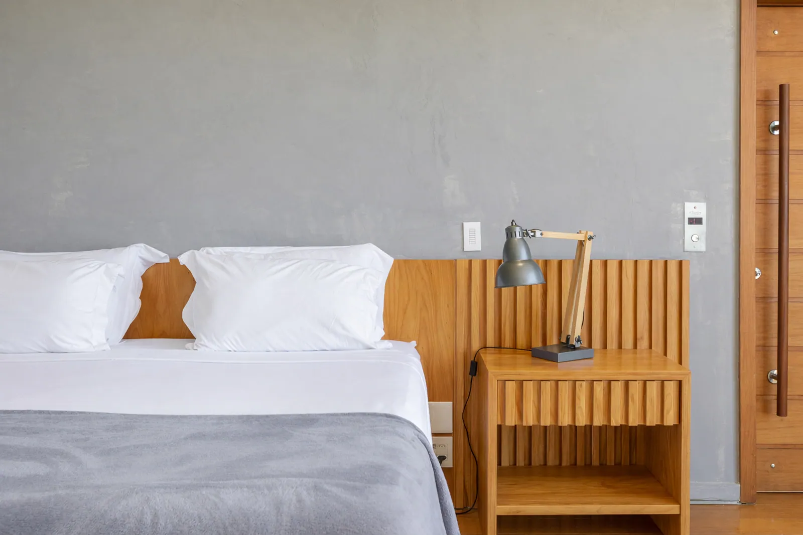 Dormitorio con cabecero de madera y lámparas de lectura