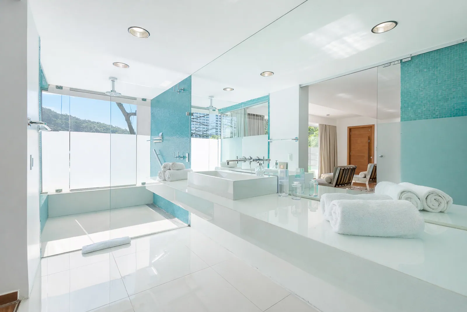 Baño con vidrio turquesa y encimera de dos lavabos
